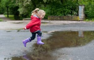 Kid jumping in a puddle on a rainy day