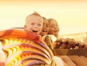 Kids on roller coaster in the summer smiling