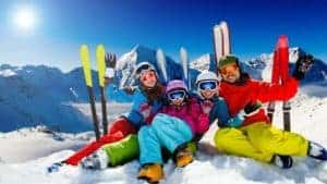 Family sitting on snow middle of skiing 