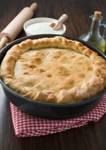 Homemade pie by rolling pin on red placemat