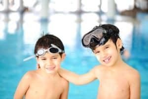 Two boys standing by indoor pool