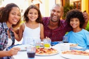 Family eating pizza at an outdoor restaurant.