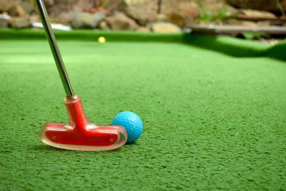 red golf club and ball on putt putt course