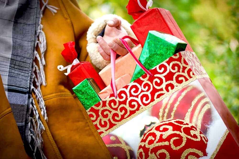 A woman carrying gifts during a Christmas shopping trip.