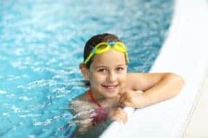 little girl with goggles swimming in the pool