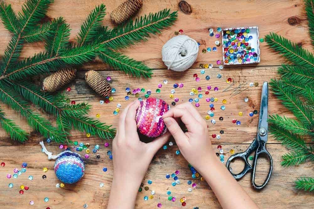 person decorating christmas ornaments with sequins