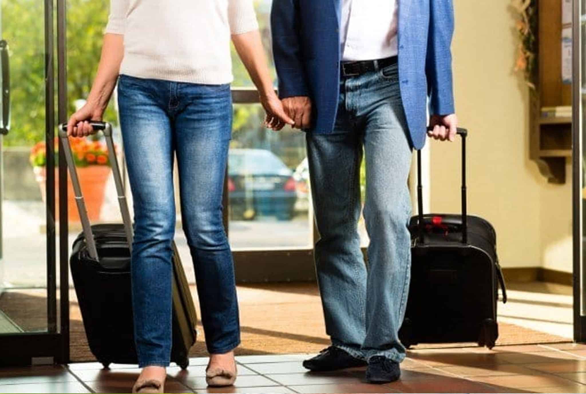 couple walking into a hotel lobby with roller luggage