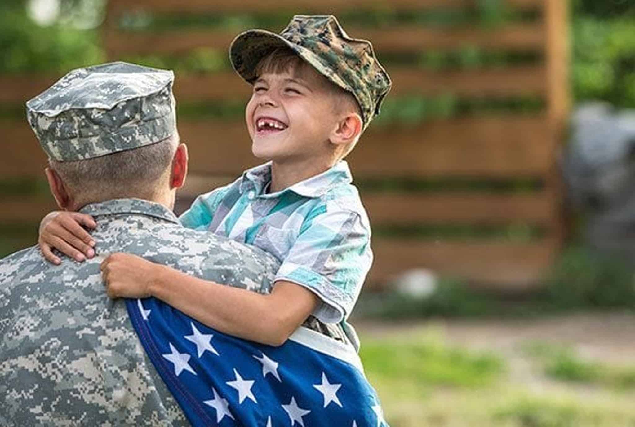 kid smiling while hugging his dad in the military
