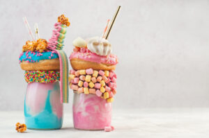 two colorful milkshakes with lots of toppings