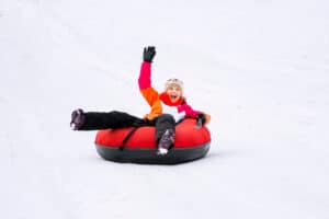 smiling girl snow tubing down a hill